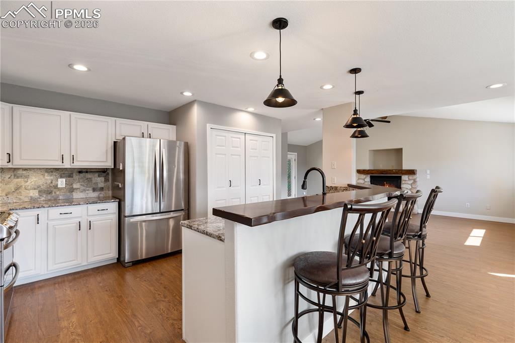Image 6 of 29: Kitchen featuring white cabinetry, granite countertops, stone backsplash, s