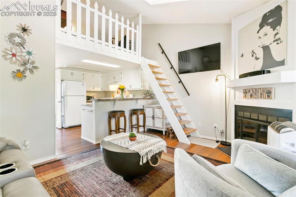 Image 3 of 17: Living room with laminate flooring, stairs leading to loft, wood burning fi