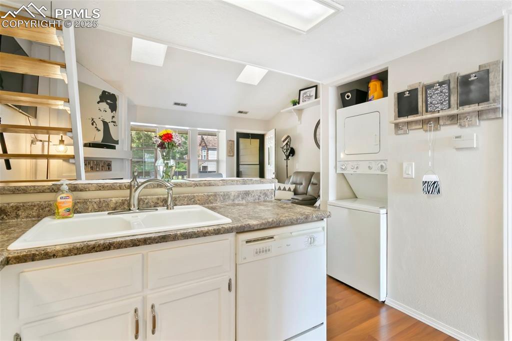 Image 6 of 17: Kitchen featuring white cabinets, dishwasher, a peninsula, light wood finis