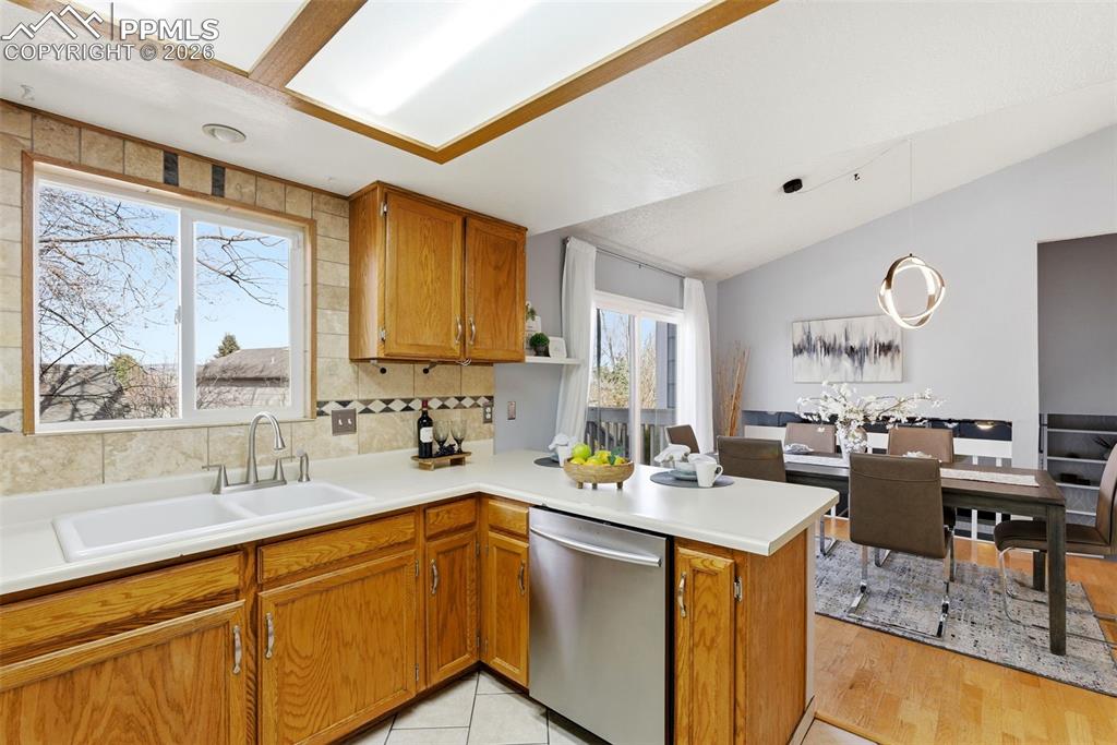 Image 11 of 45: Kitchen with wood finish cabinets, dishwasher, a peninsula, light counterto