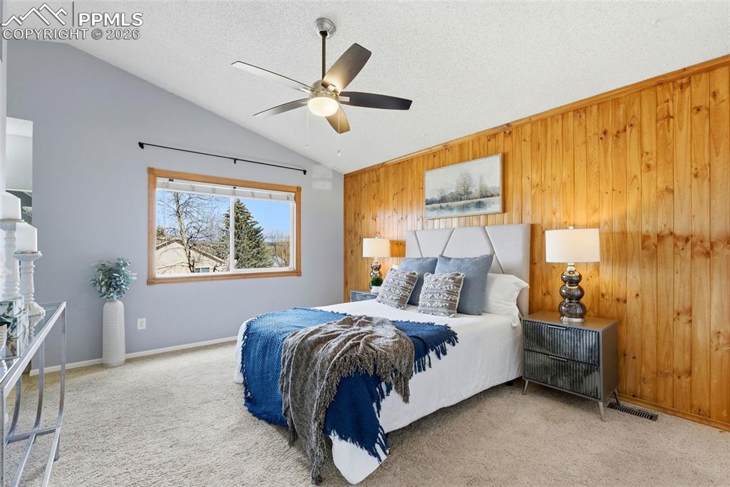 Image 13 of 45: Carpeted bedroom featuring ceiling fan and wooden walls