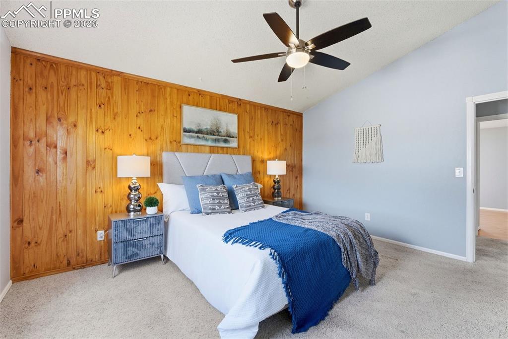 Image 14 of 45: Carpeted bedroom featuring wooden walls and ceiling fan