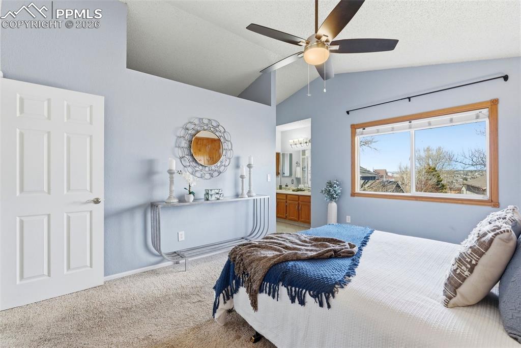 Image 15 of 45: Carpeted bedroom featuring ensuite bathroom, lofted ceiling, and ceiling fa