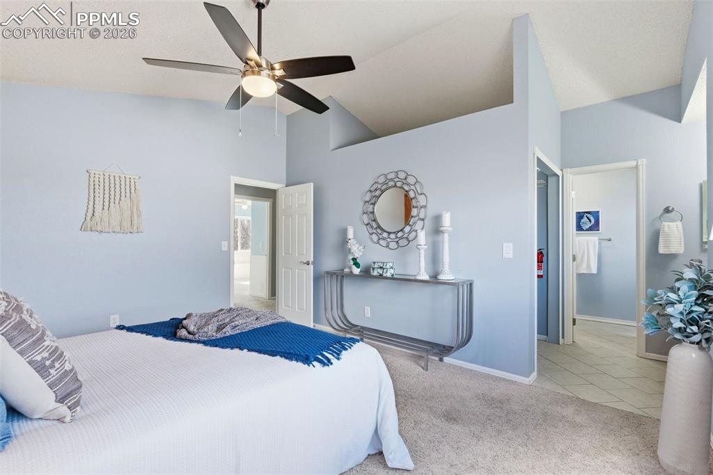 Image 16 of 45: Bedroom with light carpet, lofted ceiling, ceiling fan, and light tile patt