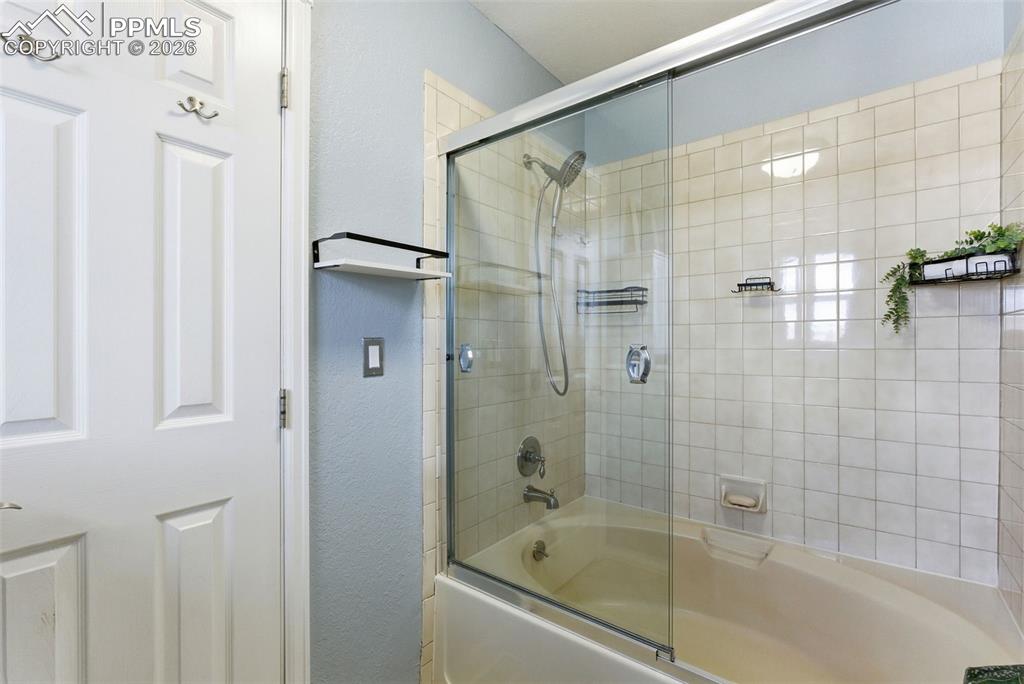 Image 19 of 45: Full bathroom featuring bath / shower combo with glass door and a textured