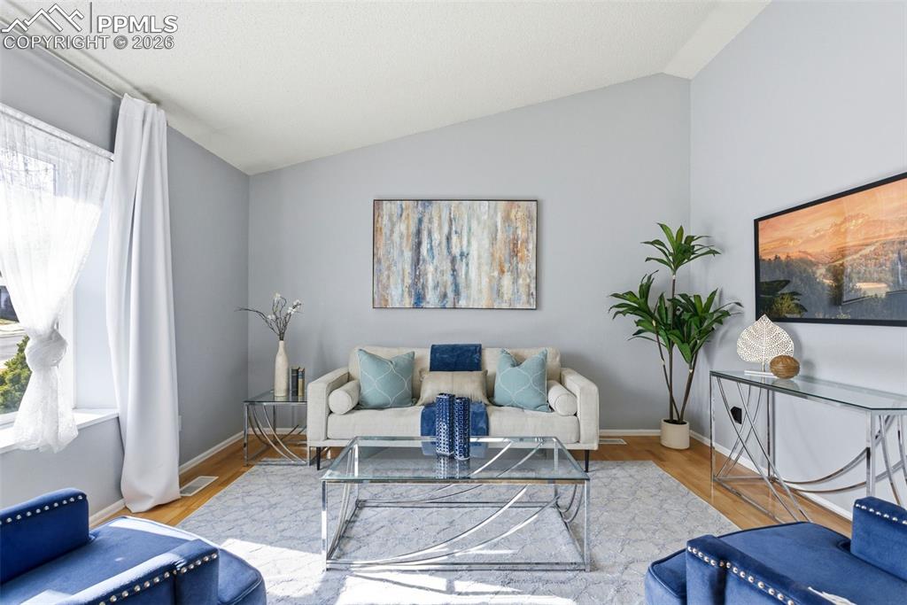 Image 2 of 45: Living area featuring vaulted ceiling and wood finished floors