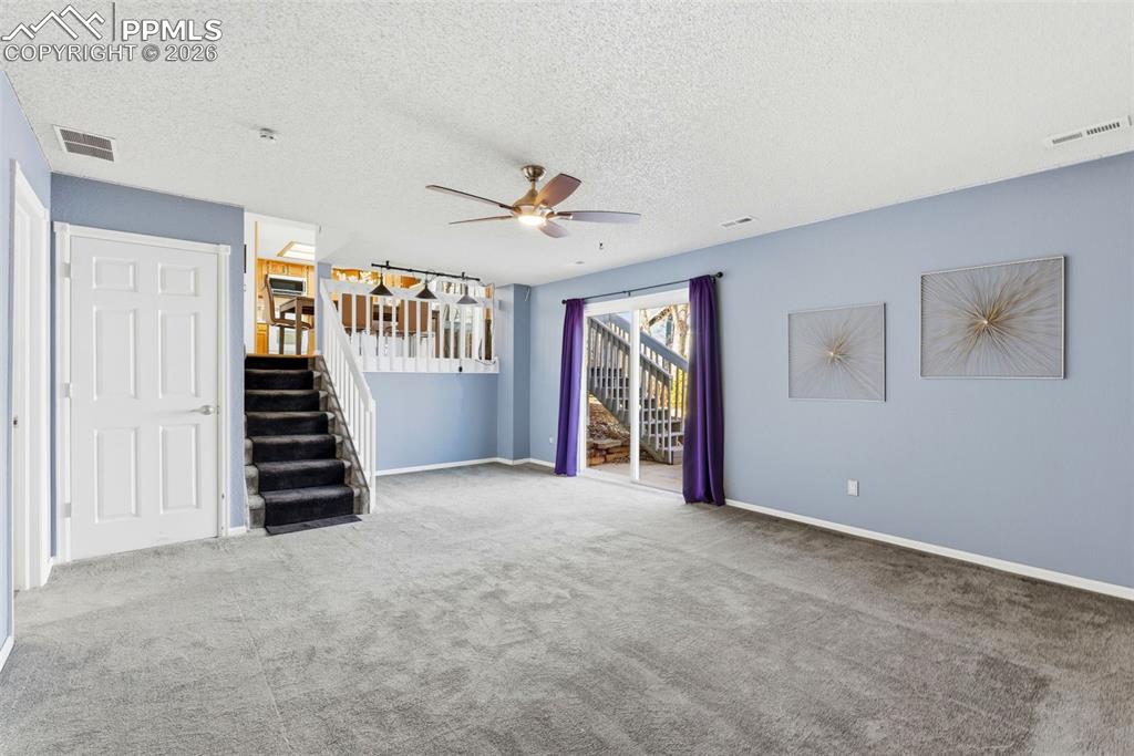 Image 27 of 45: Unfurnished living room featuring a ceiling fan, carpet floors, and a textu