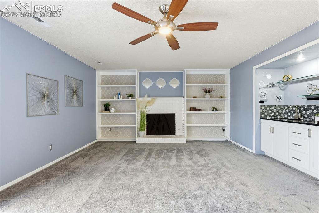Image 29 of 45: Unfurnished living room featuring ceiling fan, light carpet, a textured cei