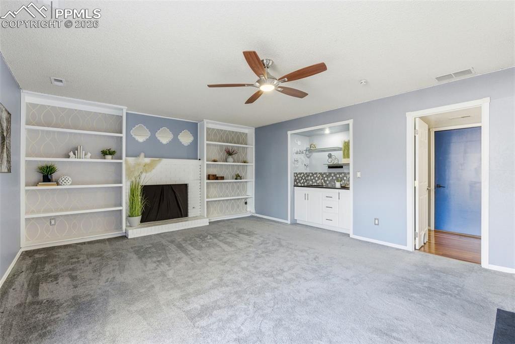 Image 30 of 45: Unfurnished living room featuring carpet floors, a ceiling fan, a fireplace