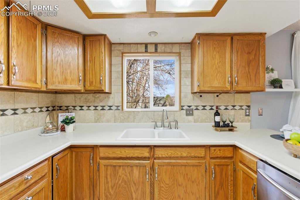 Image 9 of 45: Kitchen with wood finish cabinetry, light countertops, dishwasher, and back