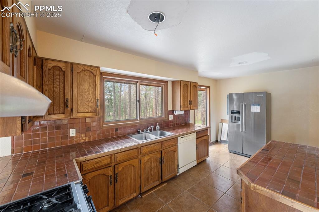 Image 7 of 43: Original kitchen with wood cabinets
and tile countertops with full height