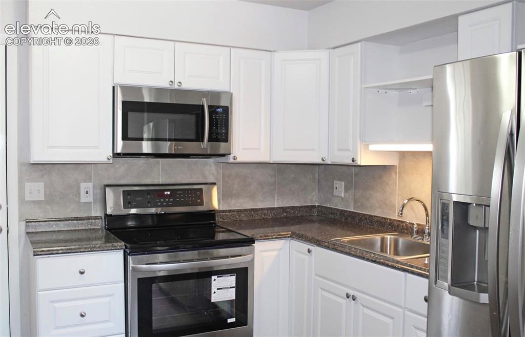 Image 5 of 12: White cabinetry, stainless steel appliances, dual basin sink, and an integr