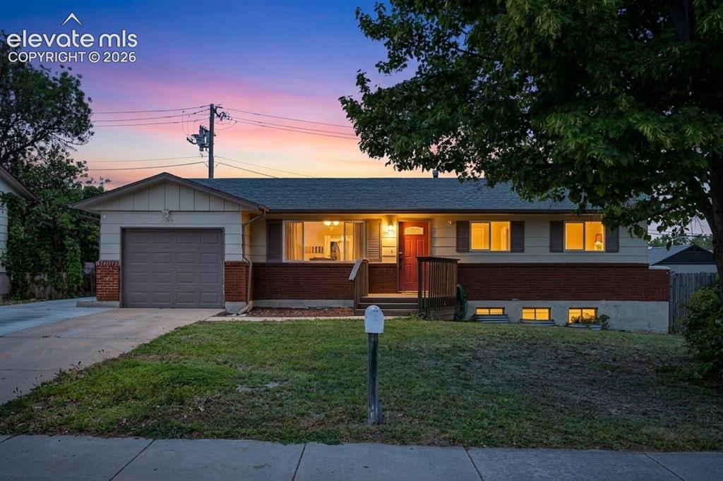 Caption: Ranch-style exterior featuring a red brick accent wall, a single-car garage, and a concrete driveway