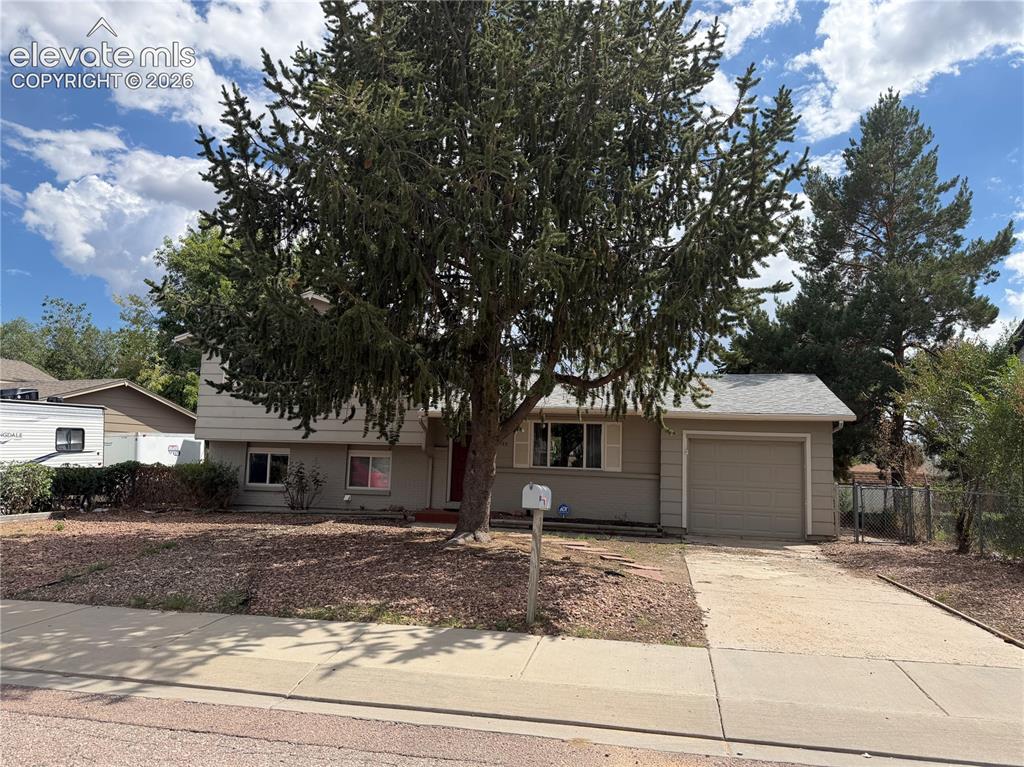 Image 1 of 17: Split-level residence featuring an attached garage, paved driveway, mature