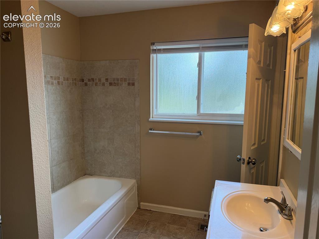 Image 11 of 17: Bathtub with tiled surround and decorative accent band. Upper level bathroo