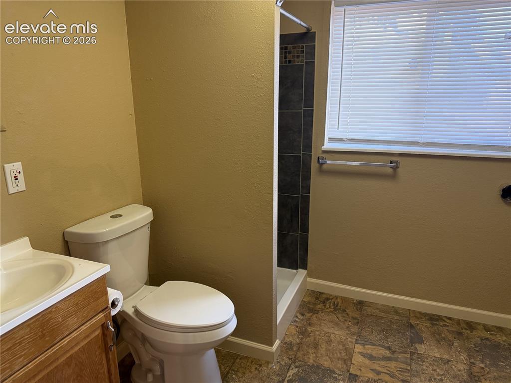 Image 14 of 17: Shower enclosure with dark tile surround, and light-toned walls in lower le