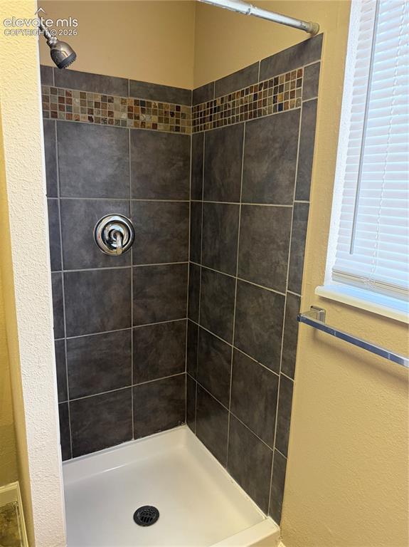 Image 15 of 17: Tiled shower stall featuring a mosaic accent band, integrated shower contro