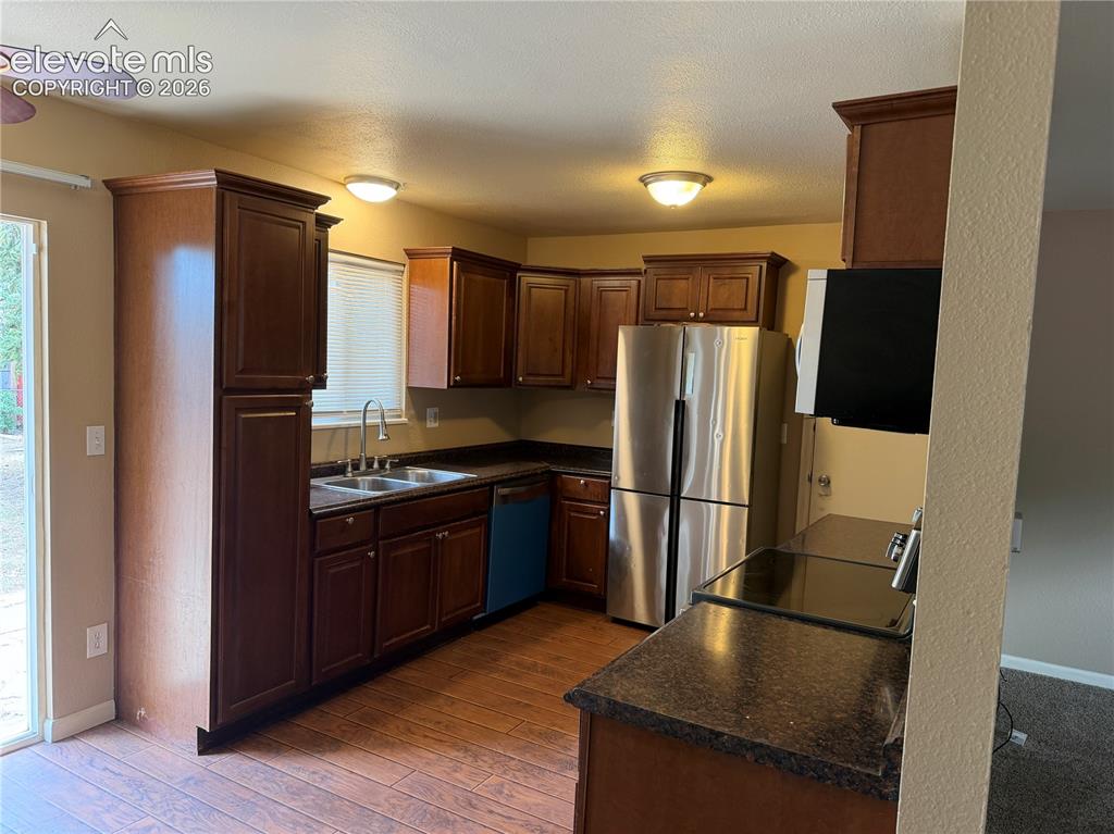 Image 6 of 17: Wood-finish flooring, dark wood cabinetry, stainless steel refrigerator, da