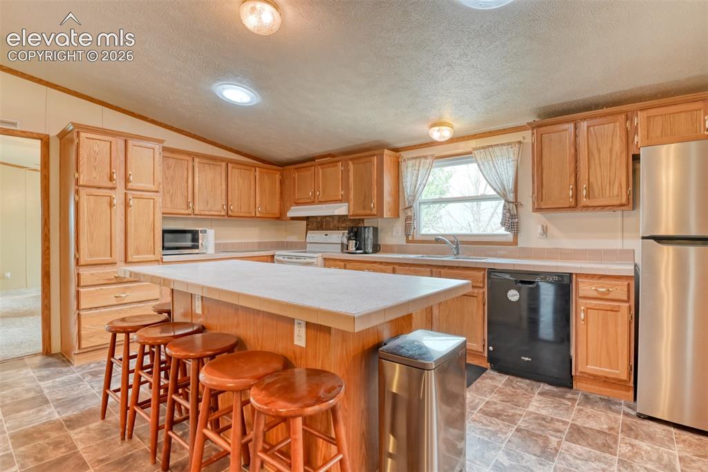Image 10 of 37: Kitchen featuring wood cabinetry, a central island with countertop, a stain