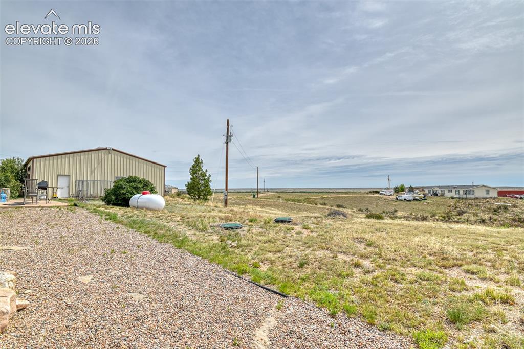 Image 17 of 37: Metal-sided outbuilding with multiple entry points and a gravel driveway