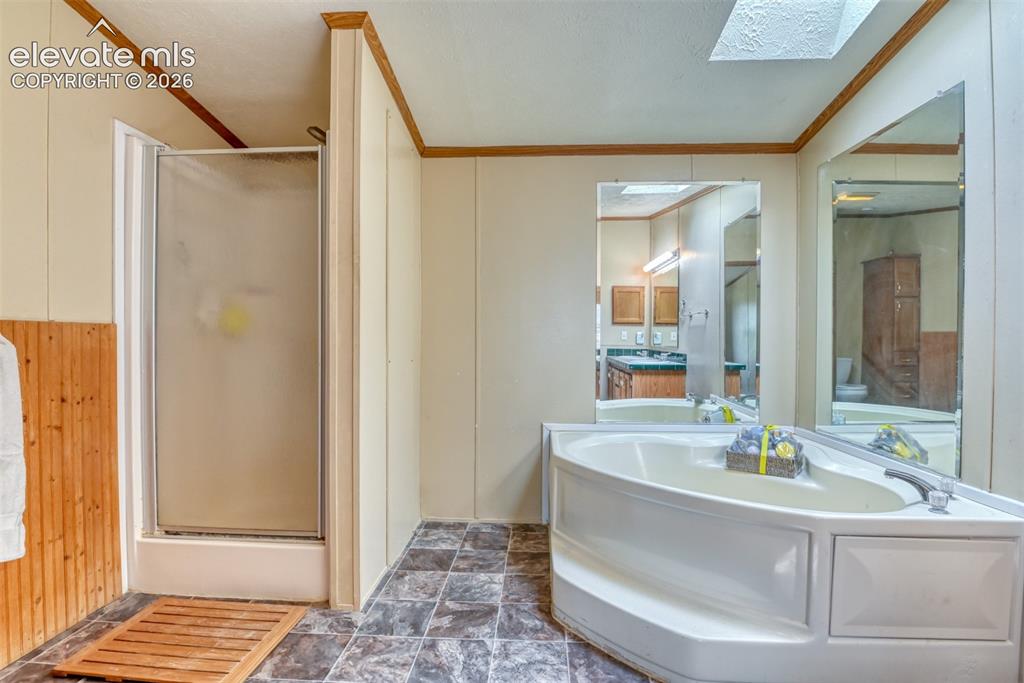 Image 21 of 37: Bathroom featuring a corner soaking tub, separate enclosed shower, and patt
