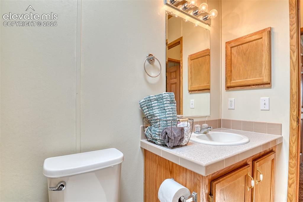 Image 22 of 37: Bathroom featuring a white toilet, light wood-finish vanity with a tile cou