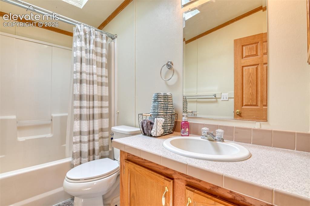 Image 23 of 37: Bathroom with white tub and shower surround, light-colored vanity with inte