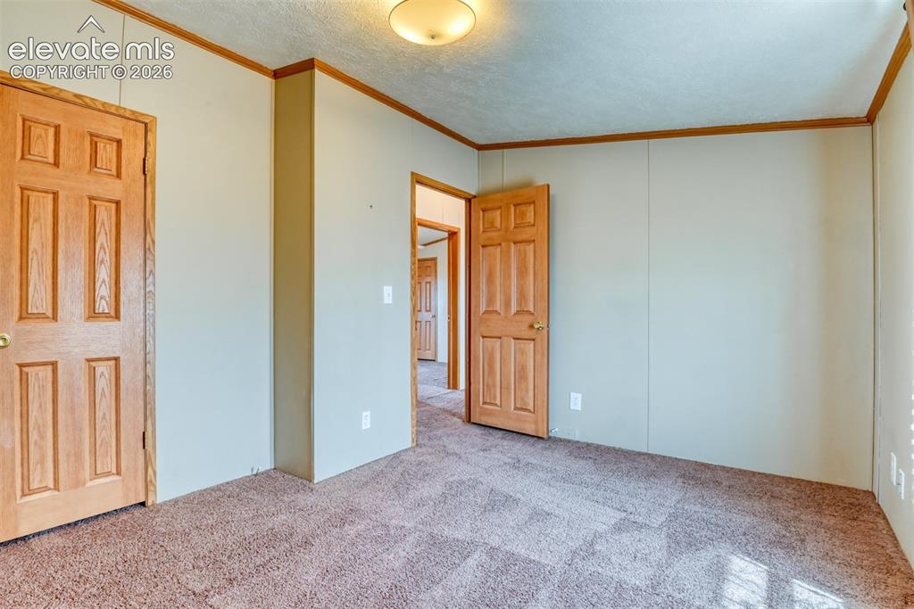 Image 24 of 37: Room featuring light-colored walls with wood trim, paneled doors, and textu