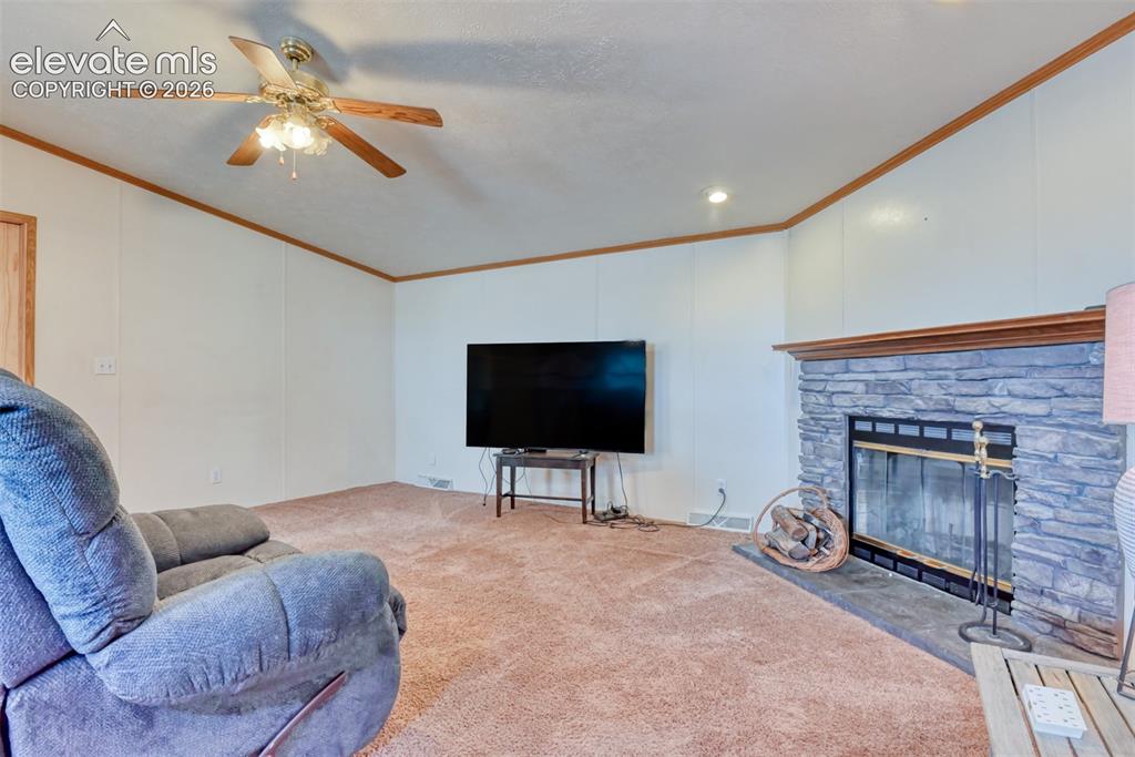 Image 25 of 37: Living space featuring a stone fireplace with a wood mantle, recessed light
