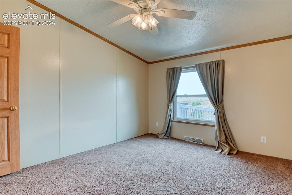Image 28 of 50: Carpeted room with a ceiling fan, a window, and a paneled wooden door