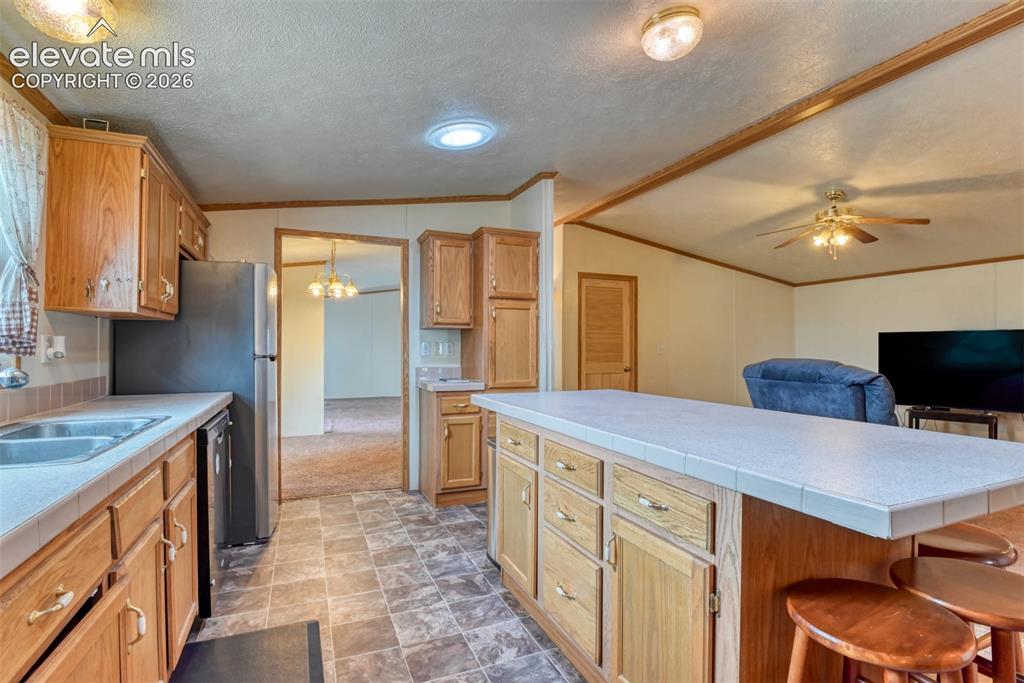 Image 29 of 37: Kitchen featuring wood cabinetry, tiled countertops, a stainless steel refr