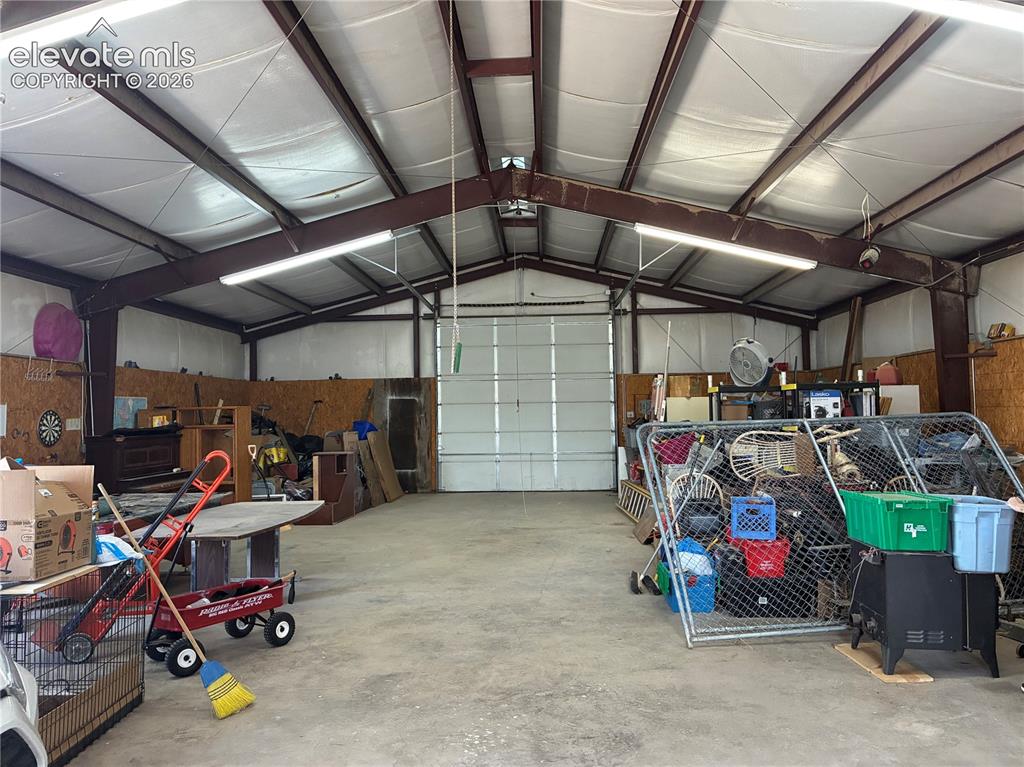 Image 3 of 37: Spacious metal building with a large roll-up door, concrete flooring, expos