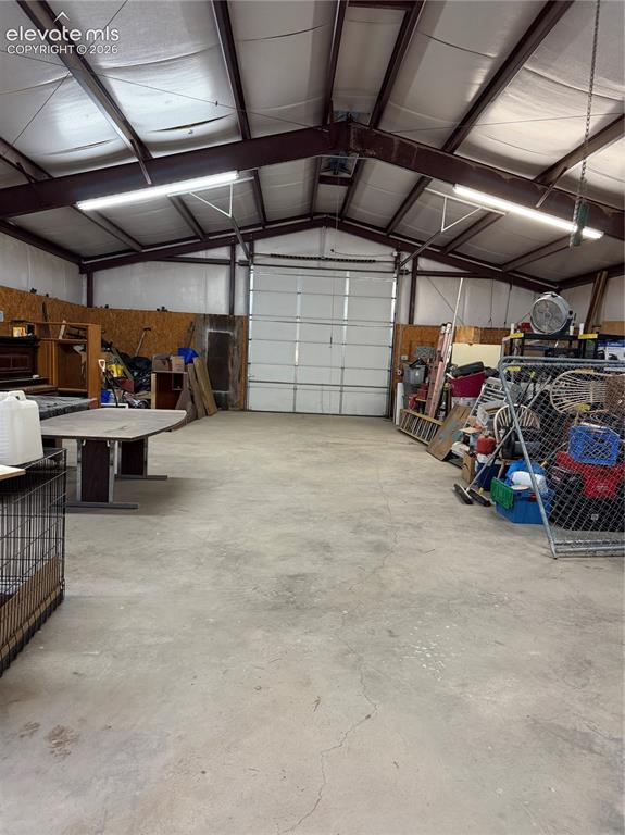 Image 37 of 37: Spacious interior featuring a large overhead door, concrete flooring, expos