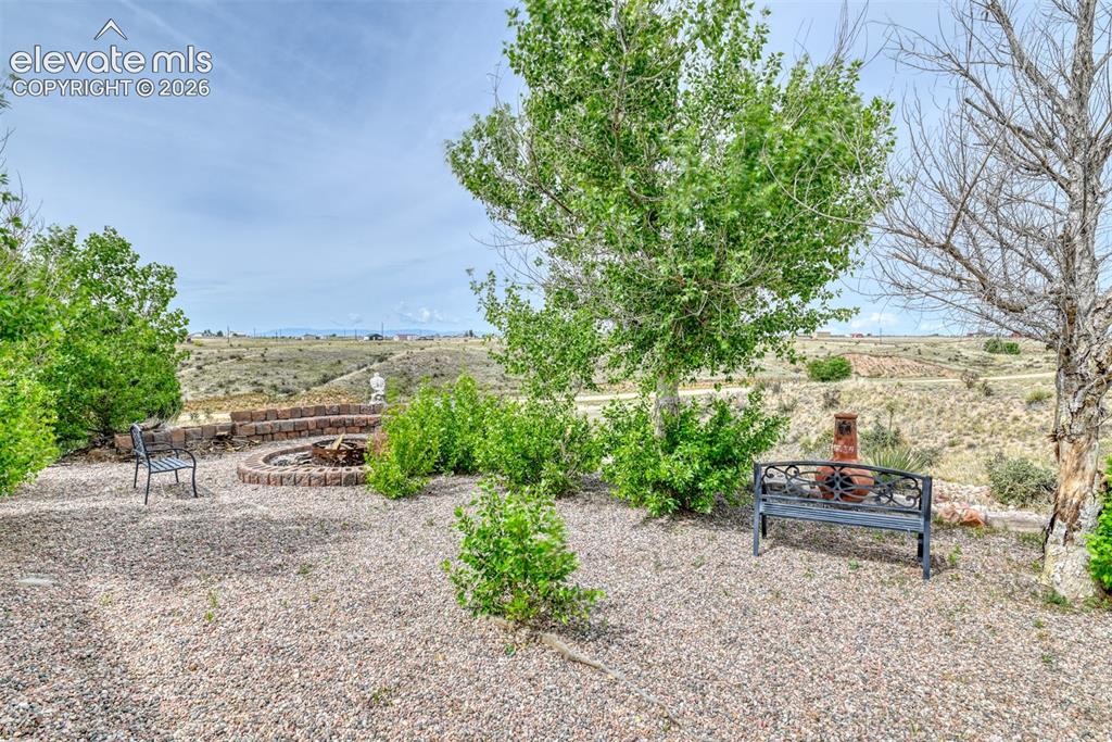 Image 6 of 37: Outdoor entertaining area featuring a circular stone fire pit, gravel groun