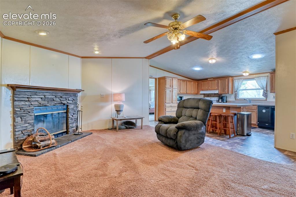 Image 8 of 37: Living area featuring a stacked stone fireplace with a wood mantle, wood-fi