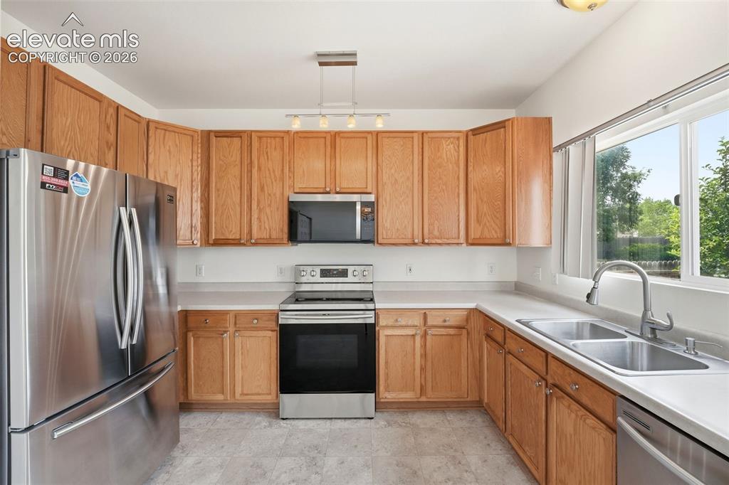 Image 11 of 48: Kitchen featuring wood cabinetry, stainless steel appliances, a double basi