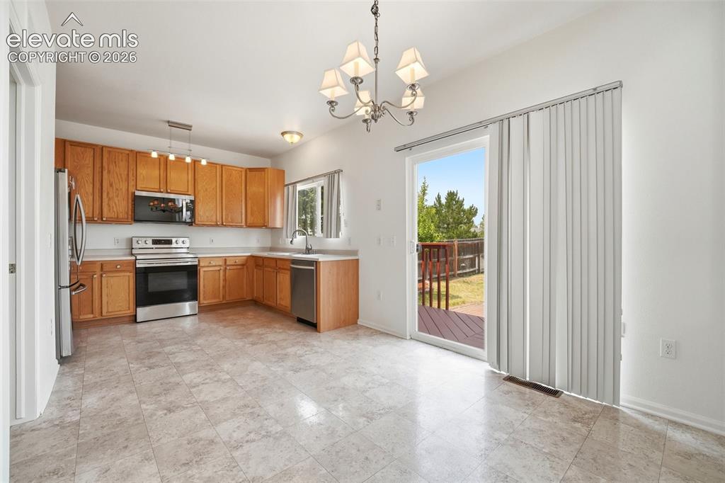 Image 14 of 48: Kitchen area featuring warm wood cabinetry, stainless steel appliances, and