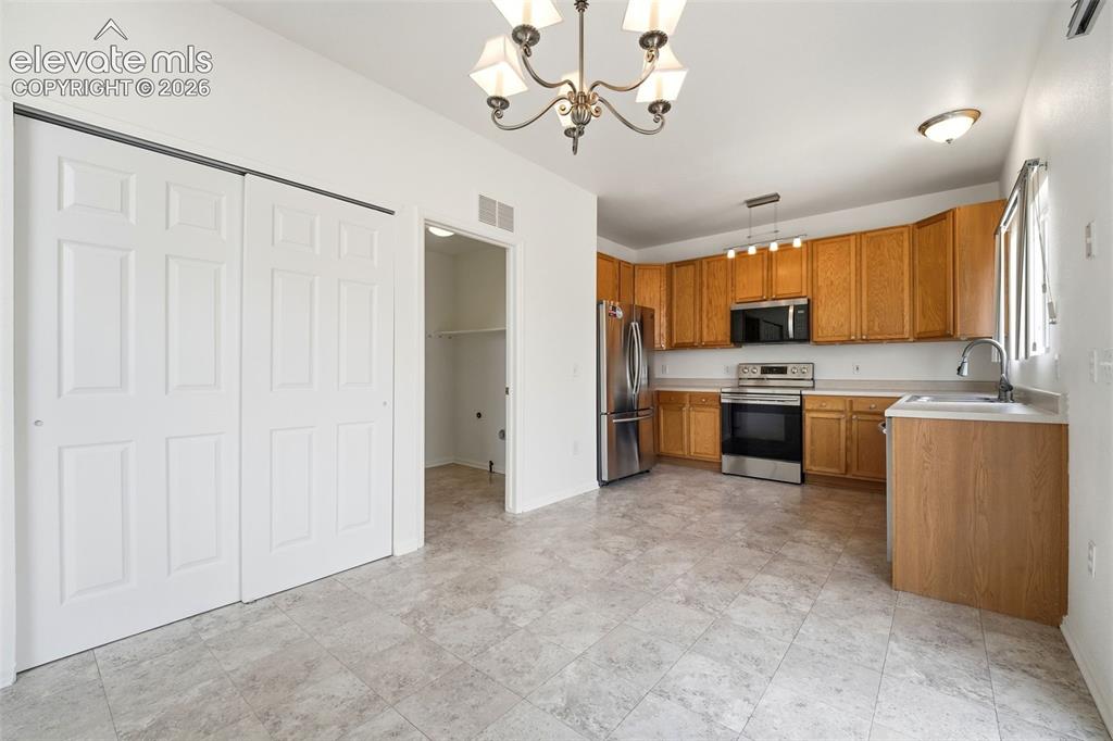 Image 15 of 48: Kitchen area featuring wood-finish cabinetry and stainless steel appliances