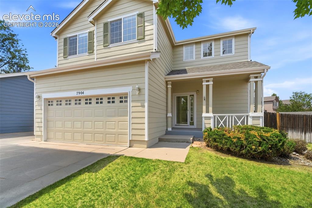 Image 2 of 48: Two-story residence featuring light-colored siding, a two-car garage with p