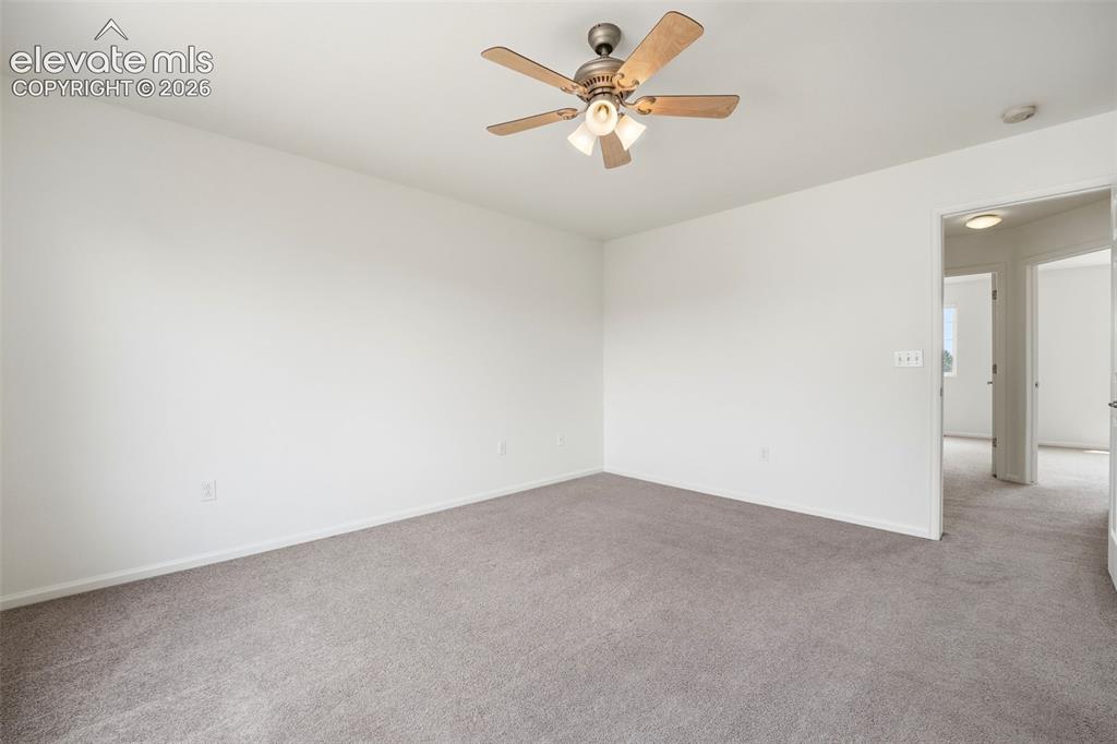 Image 23 of 48: Spacious room featuring neutral carpeting, white walls, a ceiling fan with 