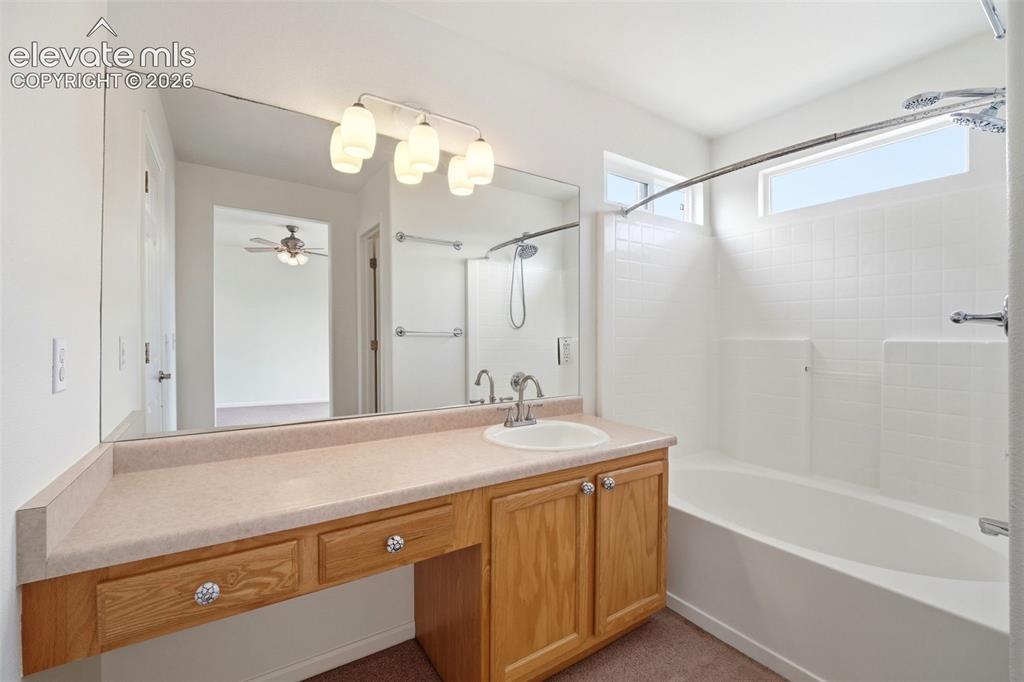Image 24 of 48: Bathroom featuring a vanity with wood cabinetry, an integrated sink, and a 