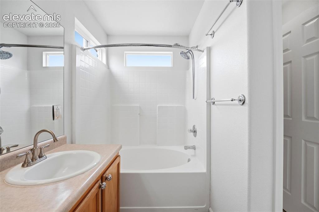 Image 25 of 48: Bathroom featuring a neutral-toned vanity with an integrated sink, polished