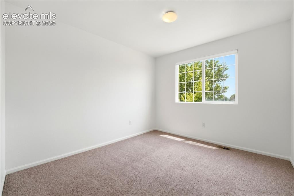 Image 28 of 48: Carpeted room featuring a double-hung window with grid inserts, a neutral c