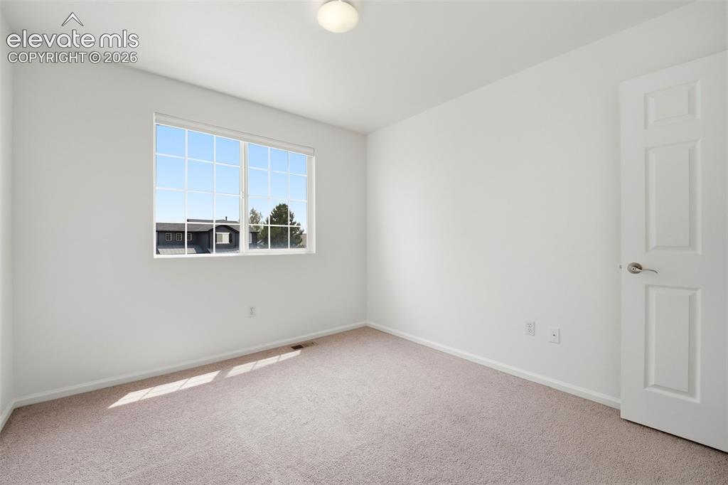 Image 29 of 48: Bright room featuring a large window with white muntins, neutral carpet flo
