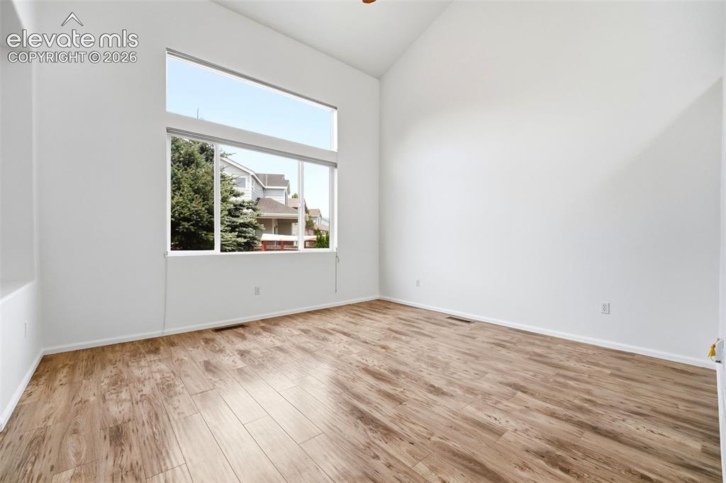 Image 3 of 48: Spacious room featuring vaulted ceilings, expansive window array, wood-fini