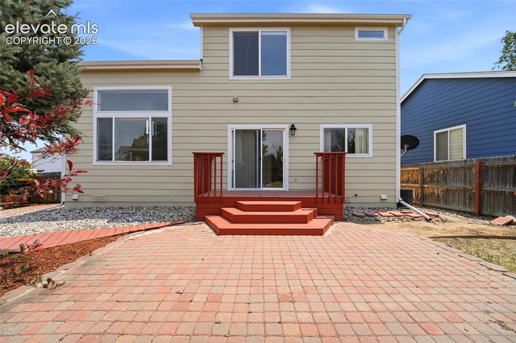 Image 32 of 48: Rear exterior featuring a brick paver patio, multi-level red-stained deck, 