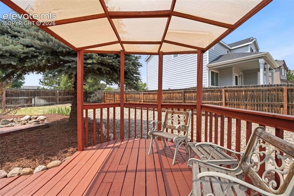 Image 37 of 48: Expansive wooden deck featuring a built-in pergola with a fabric canopy