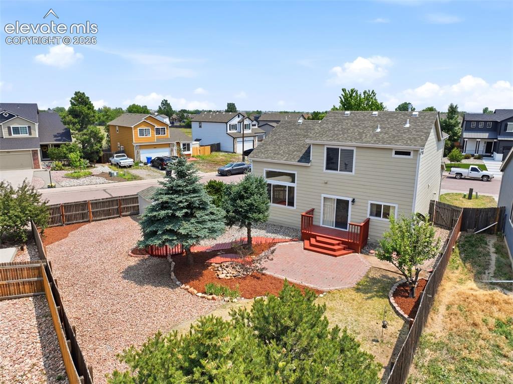 Image 41 of 48: Rear exterior featuring a red-stained wood deck, brick paver patio, and mat