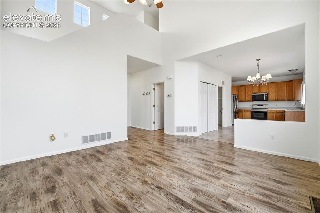 Image 5 of 48: Spacious living area featuring high ceilings, upper-level windows, and wood