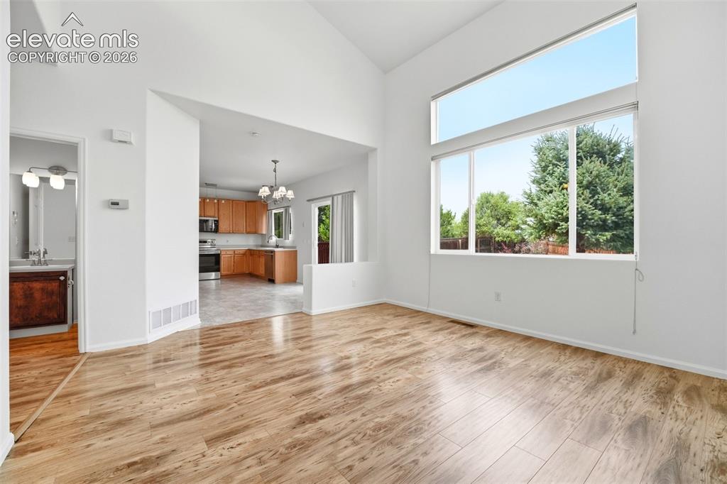 Image 6 of 48: Spacious room with wood-finish flooring, soaring vaulted ceilings, and a la